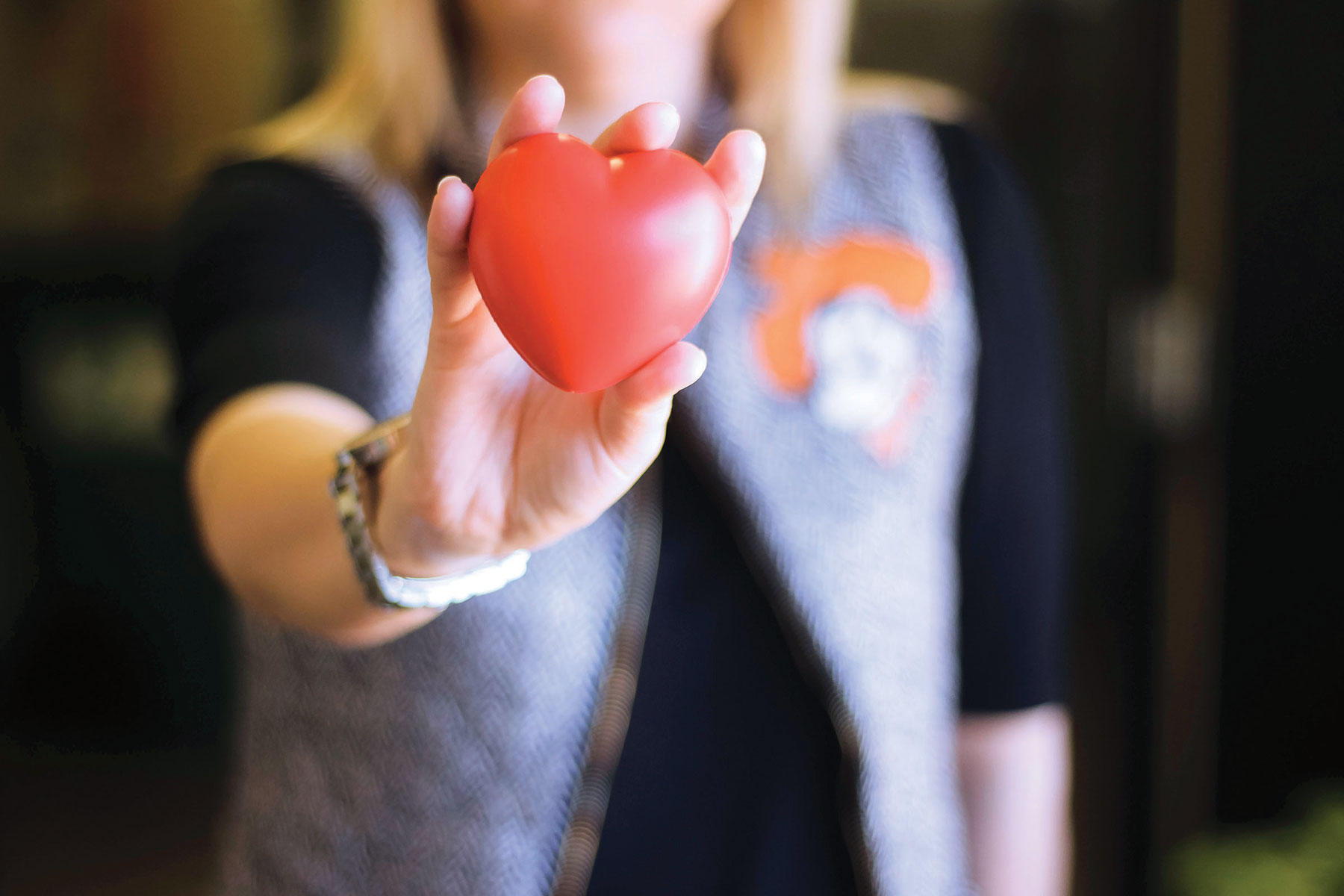 A woman holding a soft red heart shaped stress ball.
