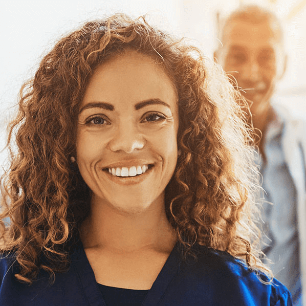 A woman in the foreground and a man in the background smiling.