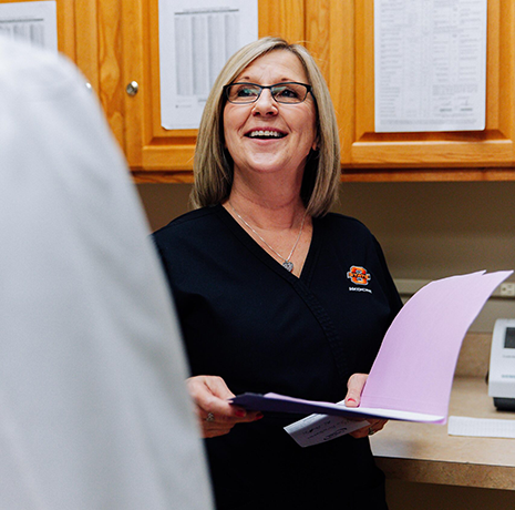 A medical professional smiling and holding a folder.