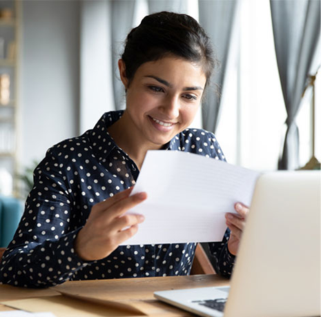 A smiling woman reading a piece of paper.