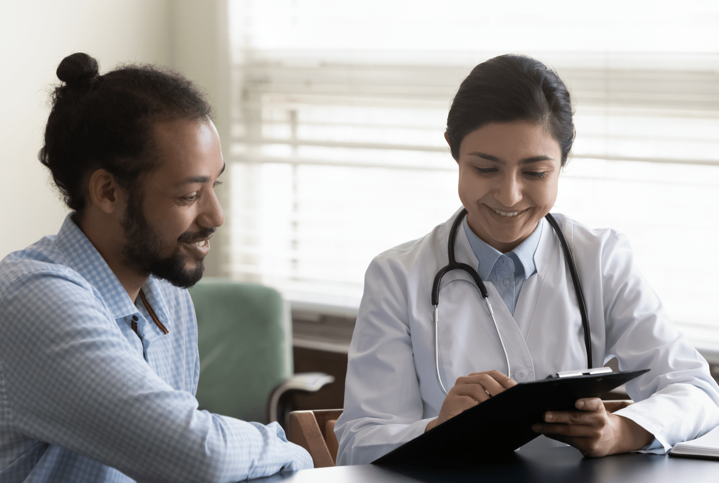 HIV Testing A doctor and a man looking at a clipboard together smiling.