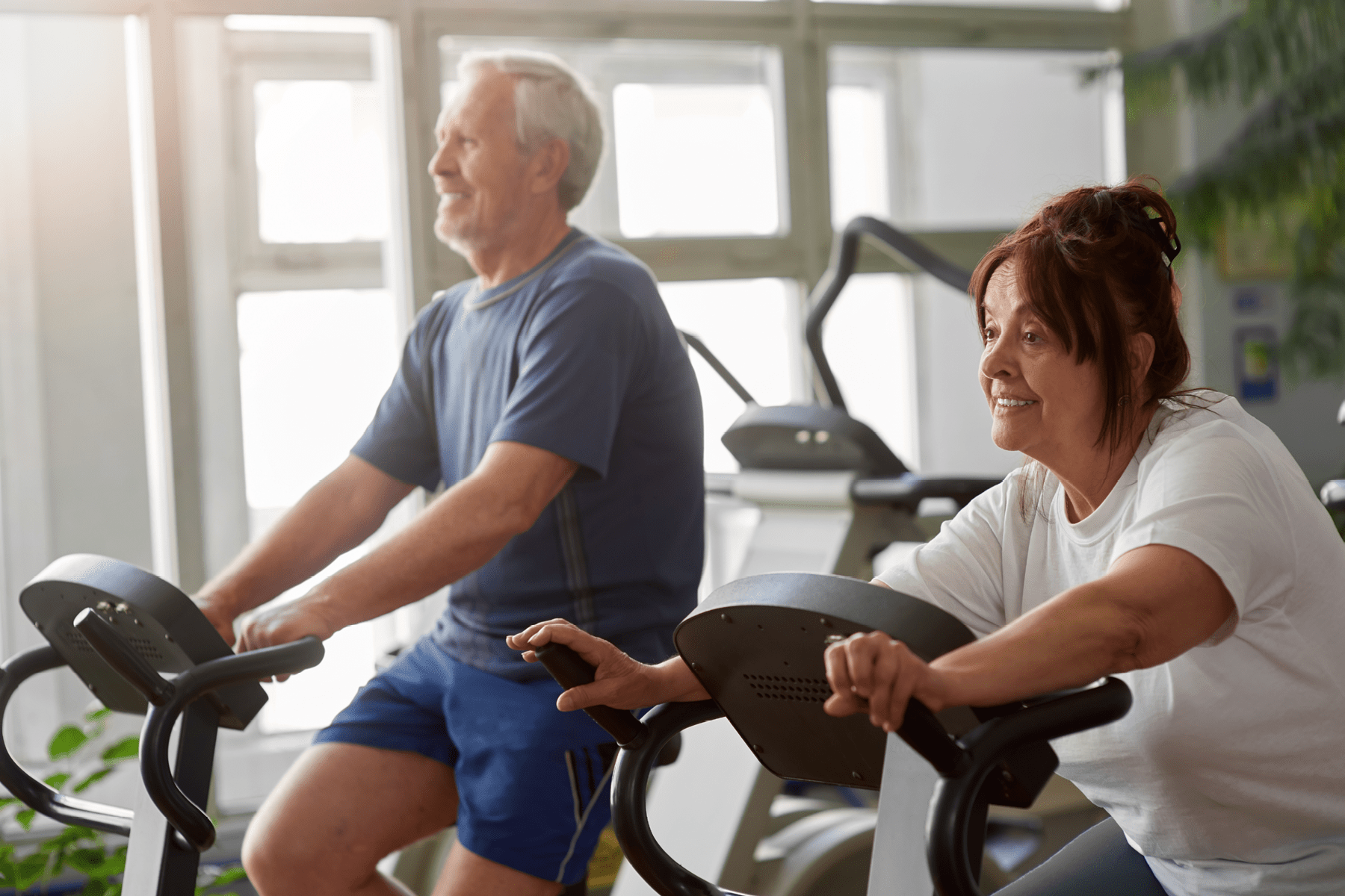 Care Connections Heart Exercise Two adults ride stationary bikes.