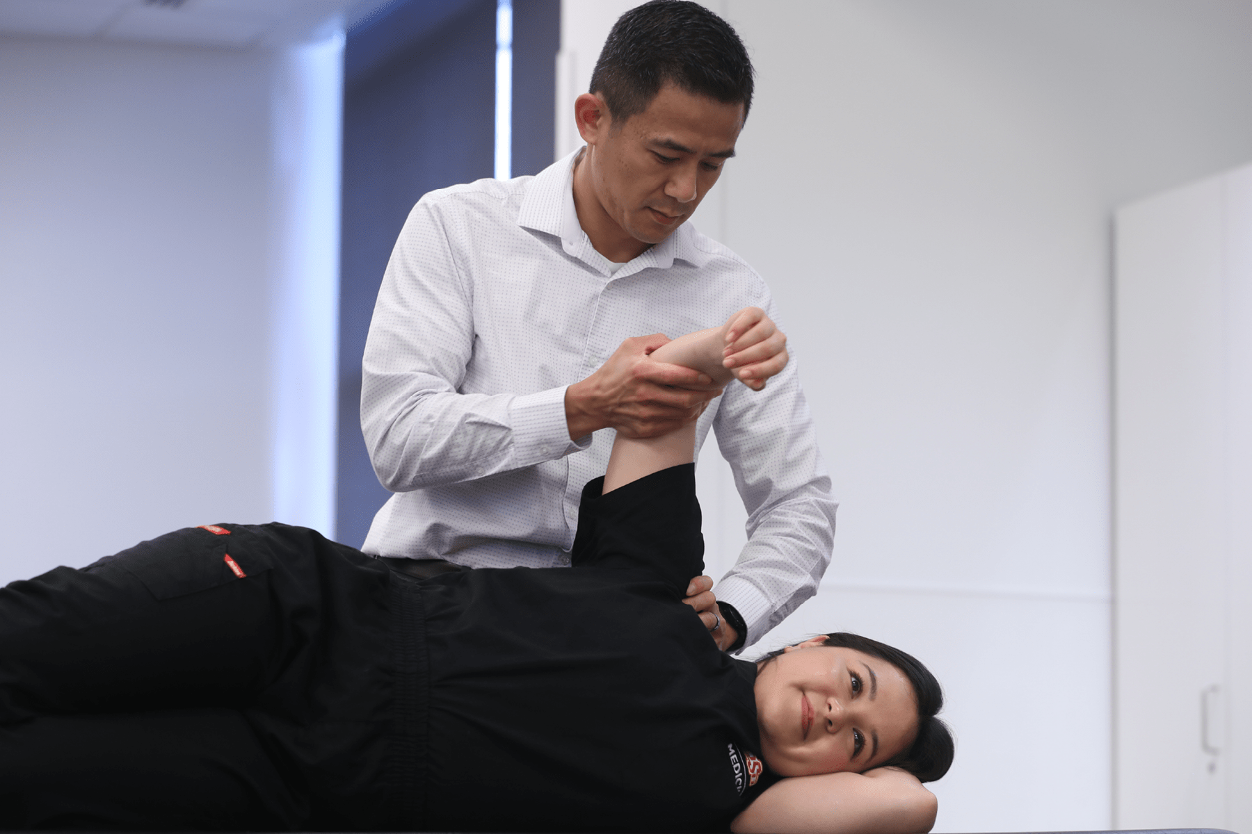 An osteopathic physician manipulates a patient's arm.
