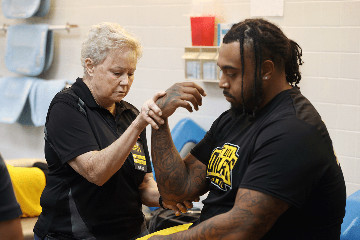 An osteopathic physician manipulates a patient athlete's wrist.