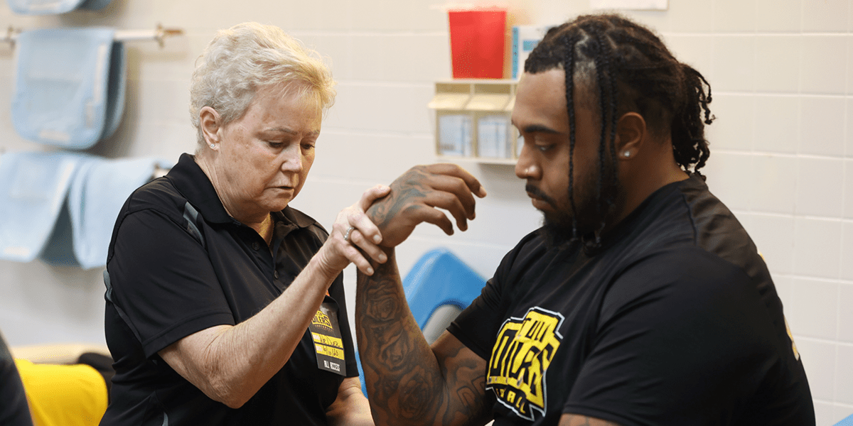 Facebook OMM Sports2 An osteopathic physician manipulates a patient athlete's wrist.