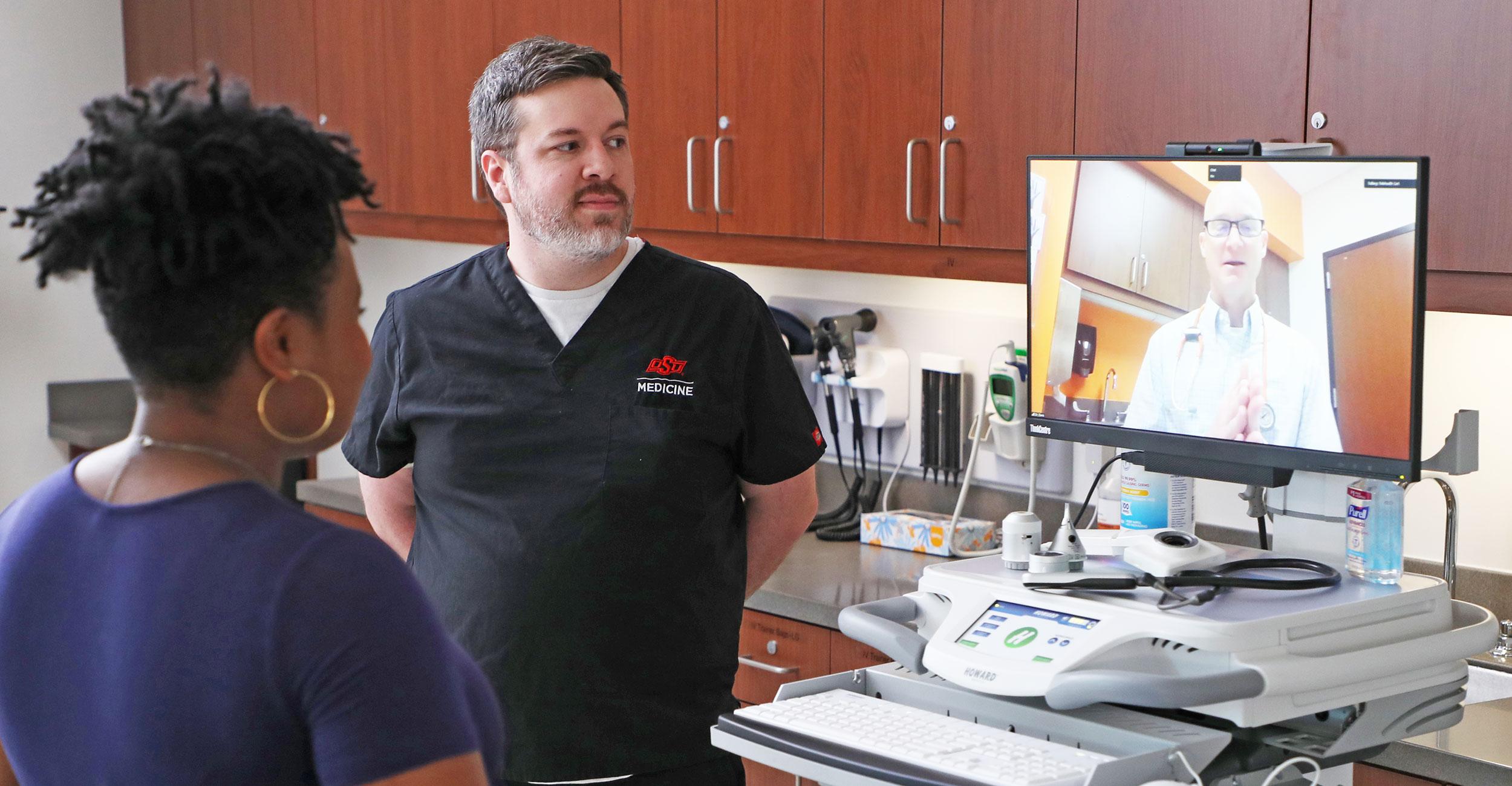 Virtual Care A doctor appears virtually to speak with a nurse and a patient in an examination room.