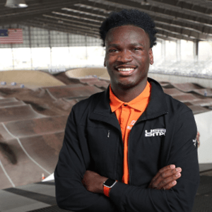 News BMX A man stands smiling with his arms folded and a BMX track in the background.
